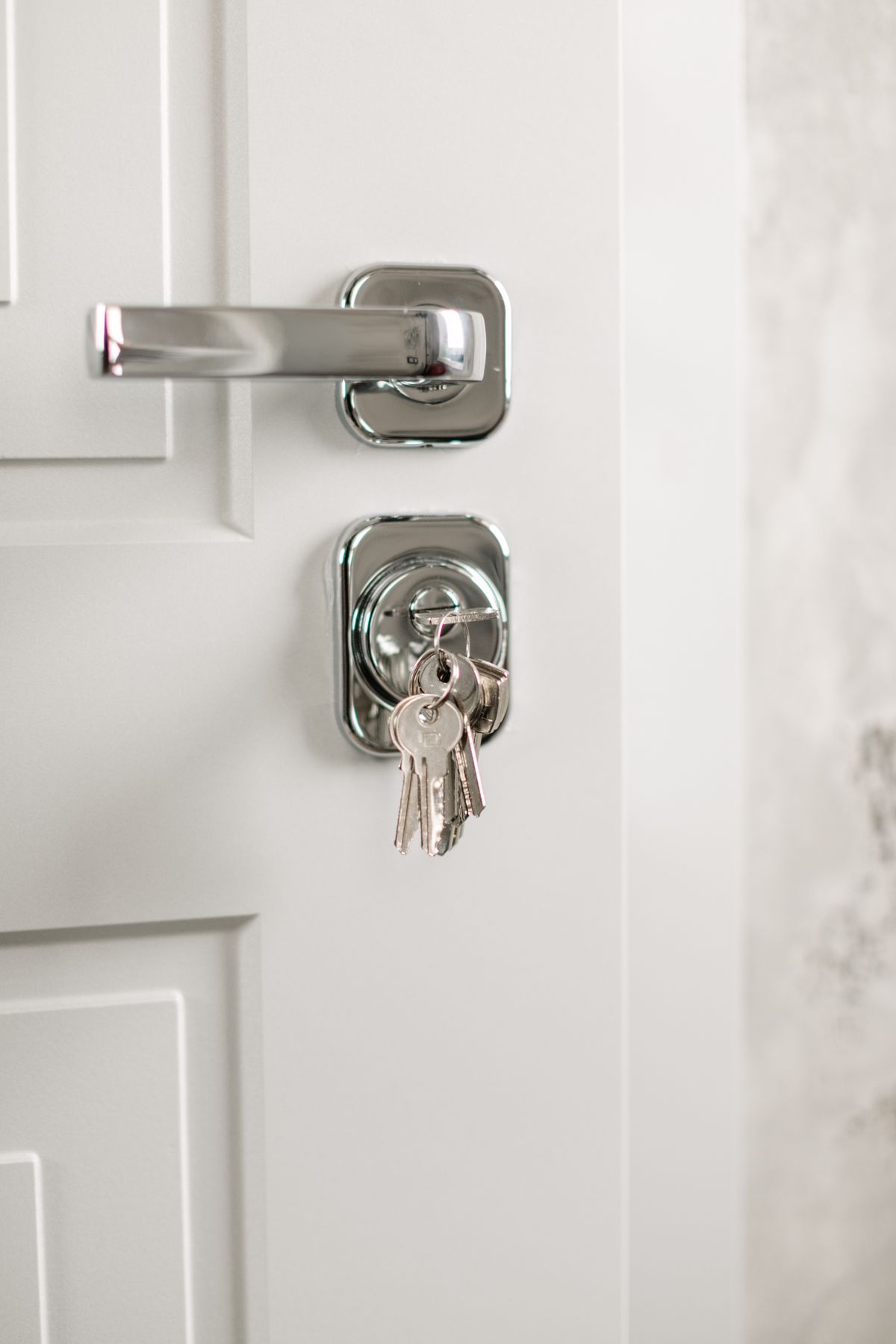 Silver door handle and lock with a ring of keys on a white paneled door.